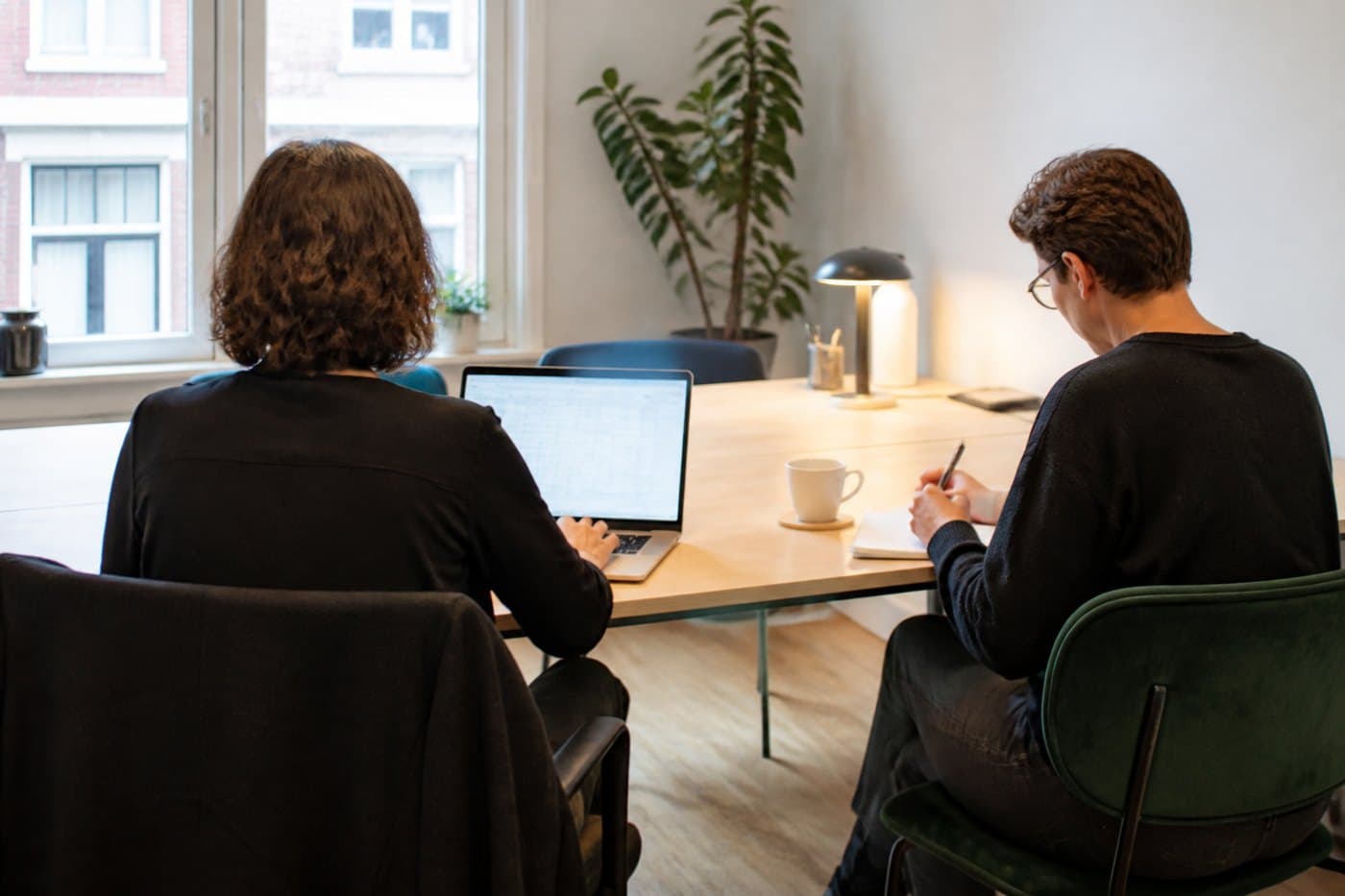 Twee mensen overleggen aan een tafel met laptops